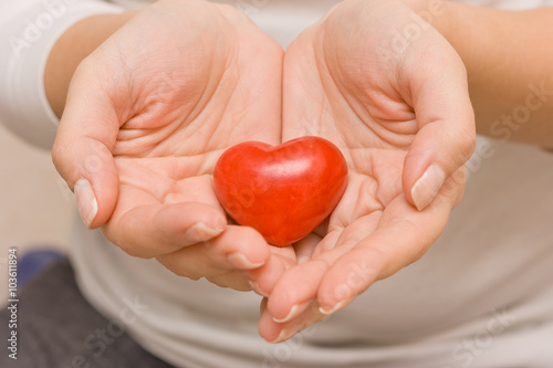 Fototapeta Naklejka Na Ścianę i Meble -  Woman hands holding a small red heart. Love. Happiness. Care. Healthcare. Valentine's day.