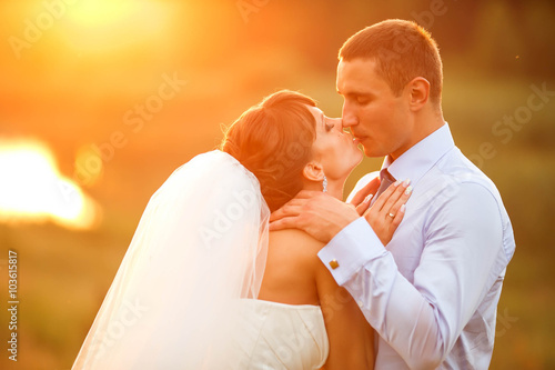 groom and bride is kissing on the background sunset in the fores