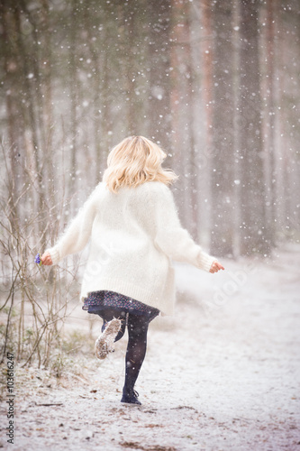 Wallpaper Mural A young woman in a white warm cardigan running in a forest and holding a bunch of first spring blue flowers. Outdoors. End of winter and beginning of spring. Easter preparations. Fairytale in forest. Torontodigital.ca