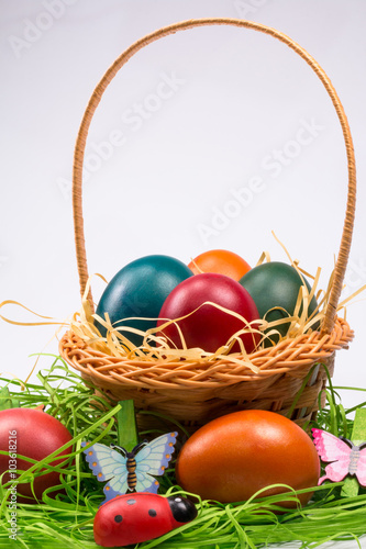 Easter eggs in wicker basket on white