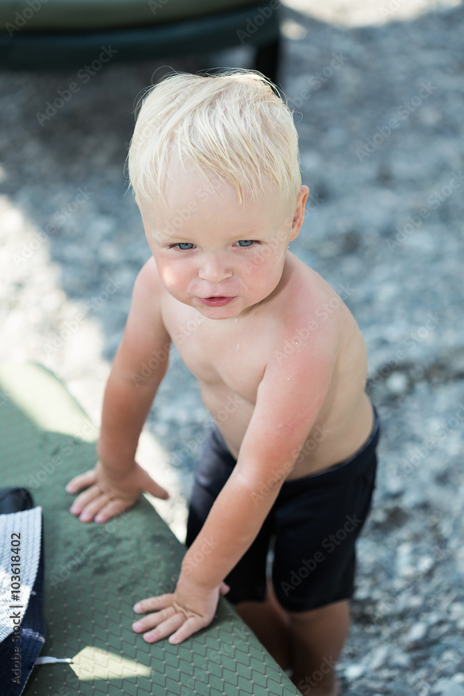 Blond boy on a beach after swimming. Selective focus Blond boy on a beach after swimming. Selective focus
