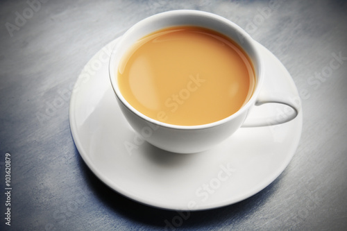 Porcelain cup of tea with milk on gray background