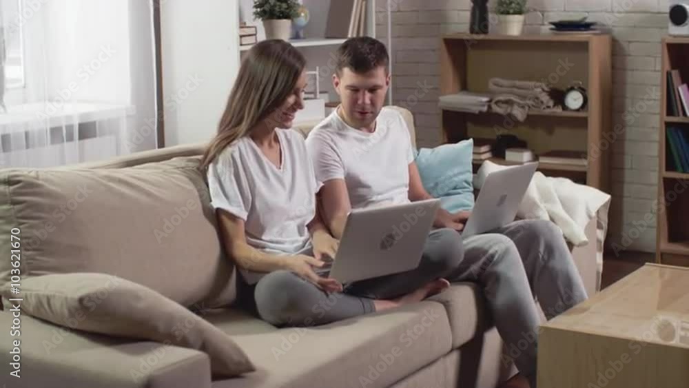 Young couple sitting with laptops in the living room and surfing the Net Young couple sitting with laptops in the living room and surfing the Net