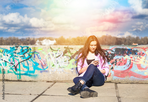 Young pretty teenage woman use her phone in city park near river  © lkoimages