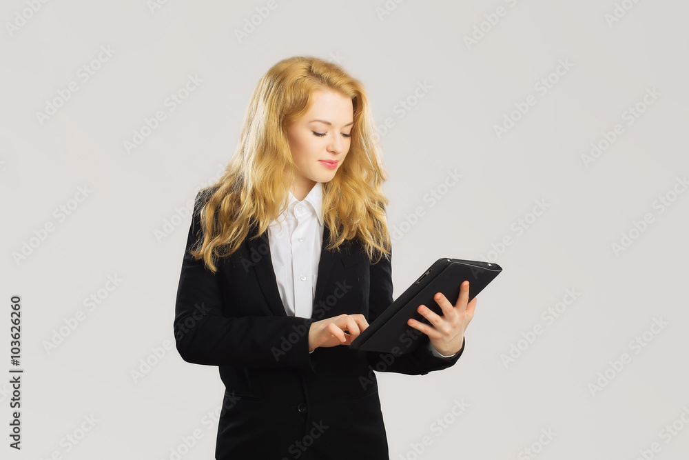 Business woman looking at tablet and smiling. Isolated grey back Business woman looking at tablet and smiling. Isolated grey back