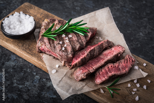 Canvas Print Grilled beef steak with rosemary and salt on cutting board