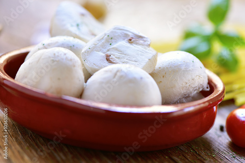 fresh mushrooms in an earthenware bowl on a wooden table