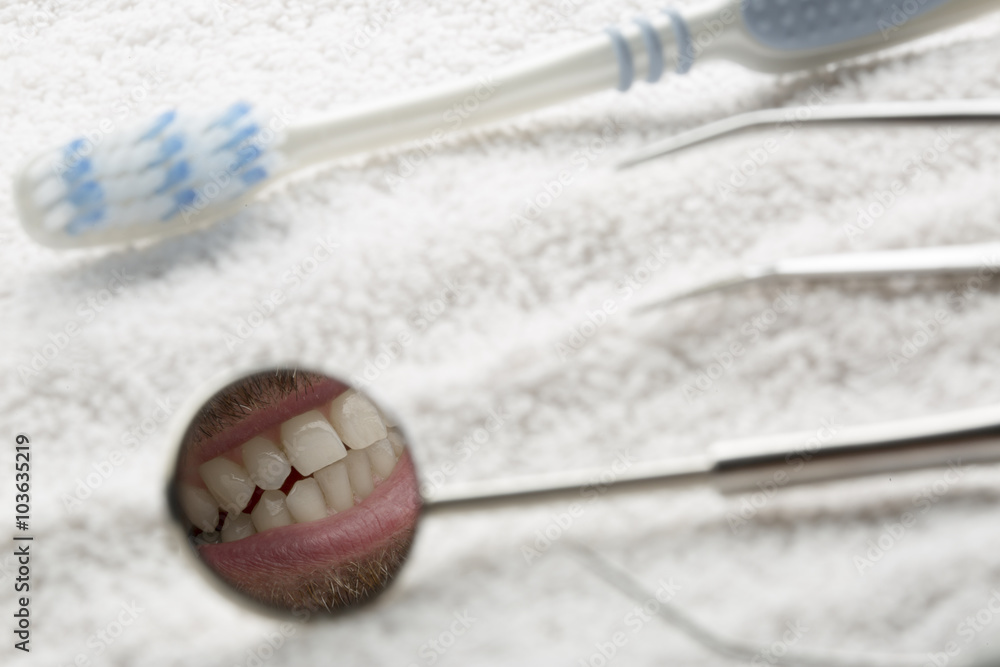 strumenti da dentista e spazzolino su asciugamano bianco con specchietto  che riflette una dentatura Stock Photo