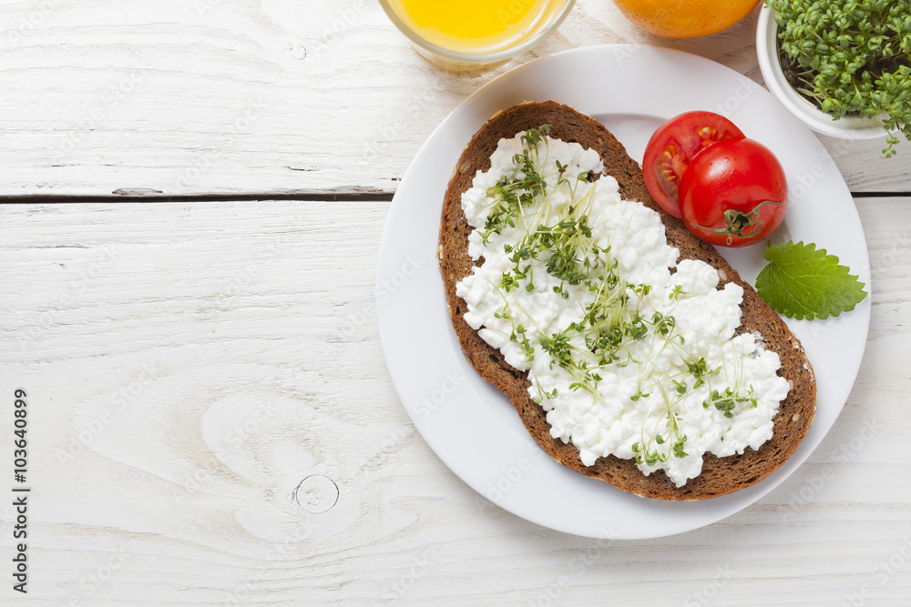 healthy spring summer low fat breakfast with orange juice,coffee,bread,cottage cheese, cress and tomatos at white wooden table