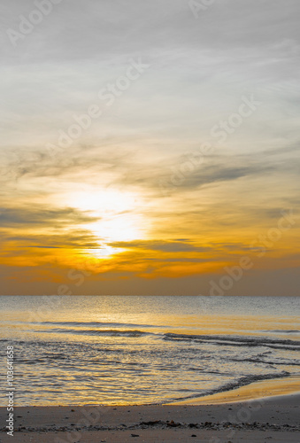 Sun sets over horizon of ocean. Sky  water and shore in the even