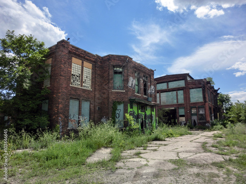 Abandoned old brick buildings with overgrown weeds and broken windows - landscape color photo