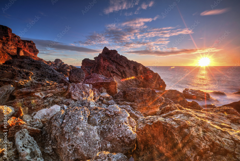 Fototapeta premium Beautiful sunrise on rocky shore and dramatic sky clouds