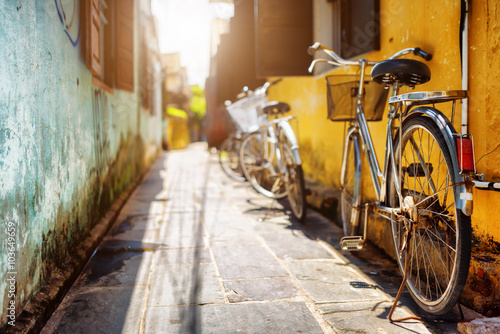 Bicycles parked near yellow wall of old house on sunny street