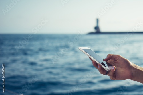 Hand presses on screen digital tablet on a sea backgroung