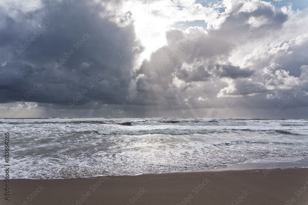 Sandstrand am Meer und Gewitterwolken mit Sonne und Sonnenstrahlen Sandstrand am Meer und Gewitterwolken mit Sonne und Sonnenstrahlen