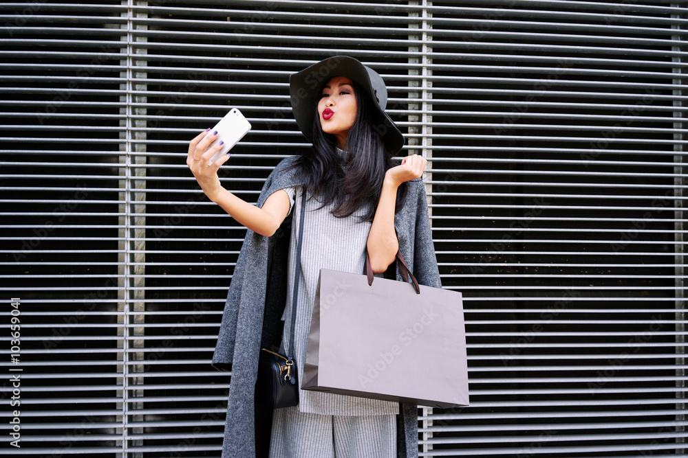 young beautiful stylishlydressed Asian girl posing and holding a blank
