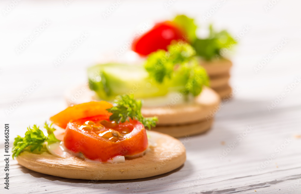 Cheese, tomatoes and greens on several cookies Cheese, tomatoes and greens on several cookies