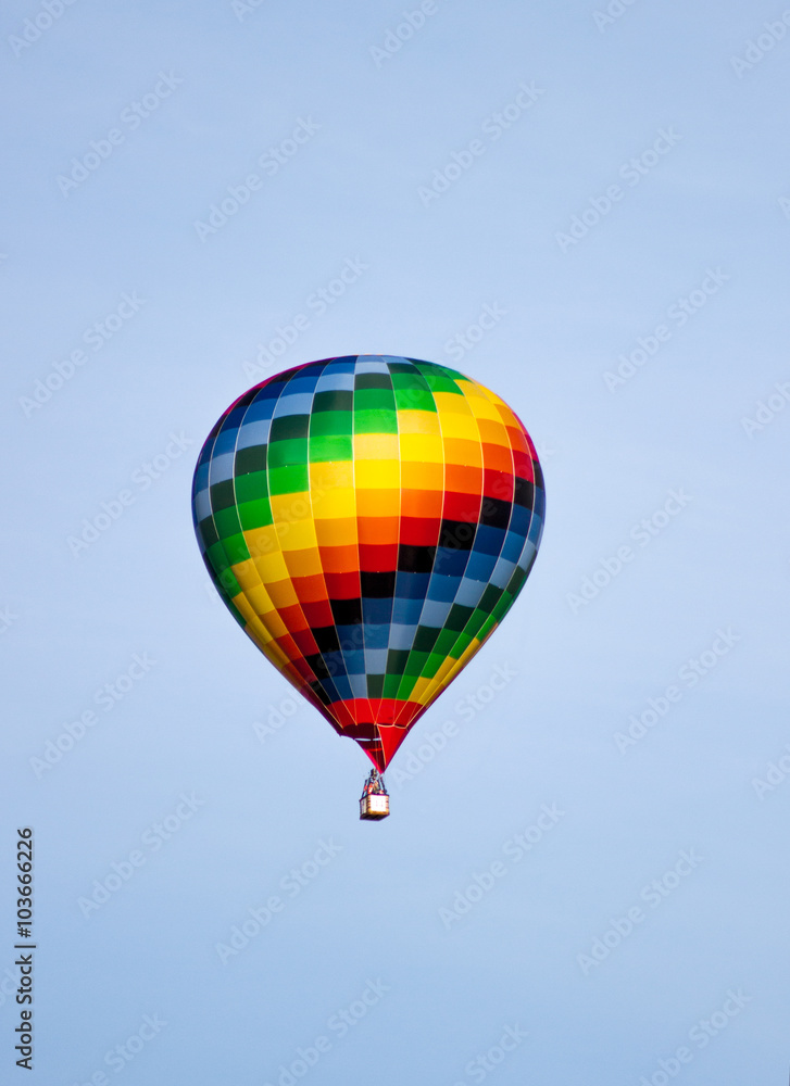 Naklejka premium Colorful hot air balloon moving up in blue sky.