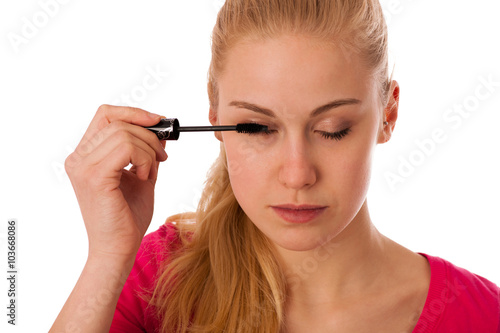 Woman applying black mascara on eyelashes  doing makeup.