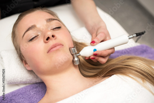 Young woman lying on massage table receiving face massage. Beaut