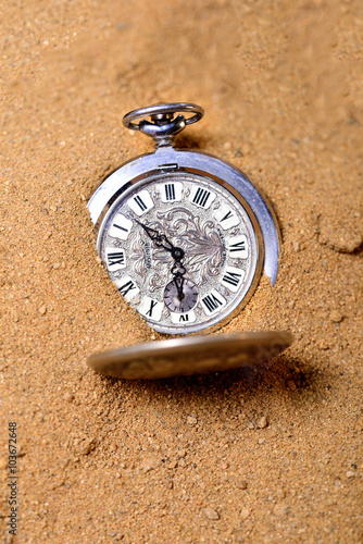 Vintage pocket watch on the beach buried in a sand