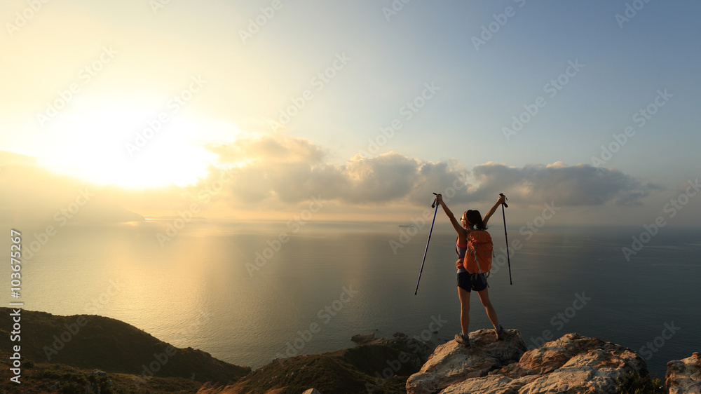cheering young woman backpacker at sunrise seaside mountain peak cheering young woman backpacker at sunrise seaside mountain peak