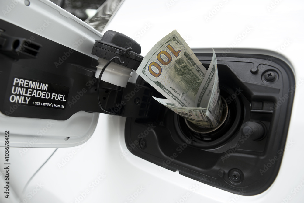 Fototapeta premium One hundred dollars USD worth of twenty dollar bills sticking out of a car gas cap.
