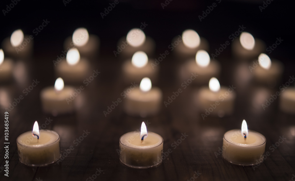 Lit Tea Light Candles on a Wooden Table (Front Focus) Lit Tea Light Candles on a Wooden Table (Front Focus)