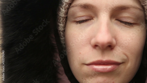 young girl in winter clothes chews the cud, outdoors