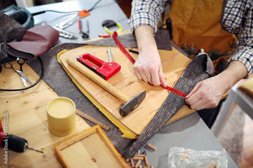 Man upholstering chair in his workshop, measure