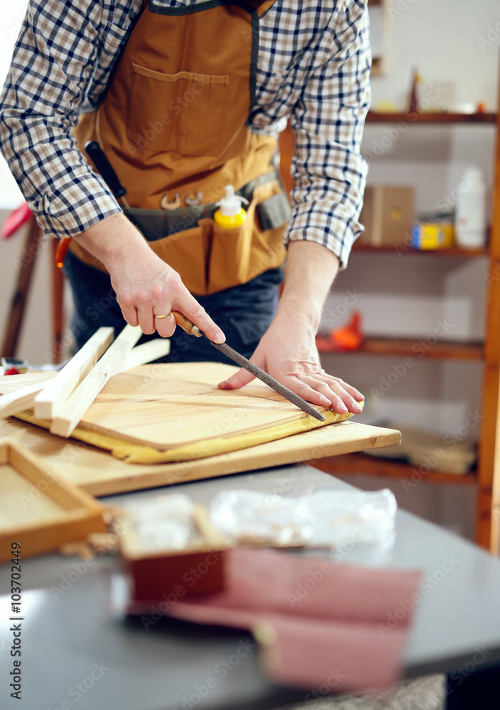 Man upholstering chair in his workshop. Carpenter using rasp in the carpentry Man upholstering chair in his workshop. Carpenter using rasp in the carpentry
