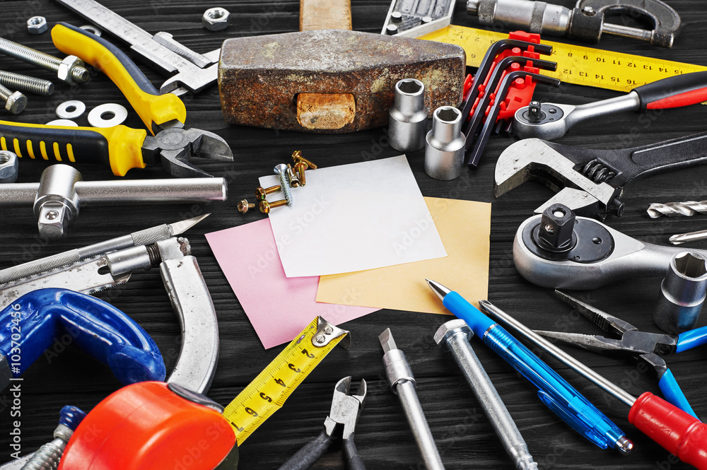 Set of tools, pen and sticky note over a wood background.