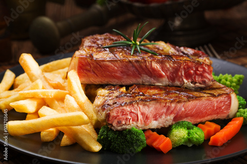 Grilled beef steak served with French fries and vegetables on a