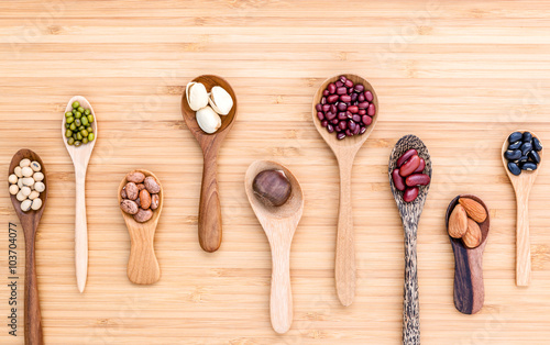 Assortment of beans and lentils in wooden spoon set up on wooden