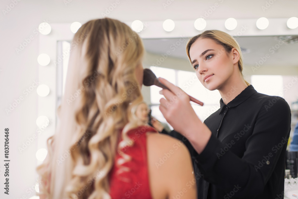 Fototapeta premium Using blush brush to apply blush on cheeks - professional makeup artist working