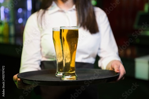 Bartender serving two glasses of beer