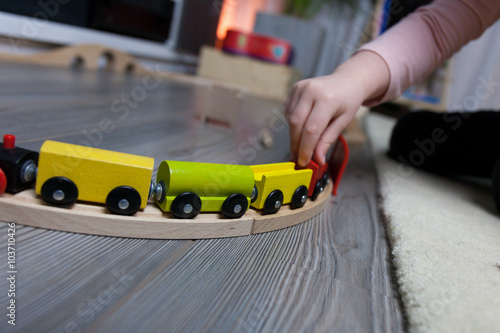 Little kid playing with railway trains on the floor at home