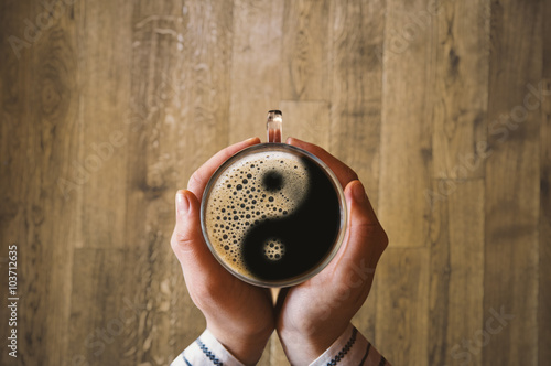 Girl holding a coffee cup with ying and yang symbol.