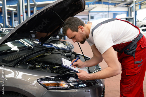 Automechaniker kontrolliert Fahrzeug in einer Werkstatt // car mechanic controlled vehicle in garage