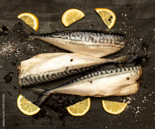 Fresh cut mackerel slices of lemon, salt, pepper on a black background