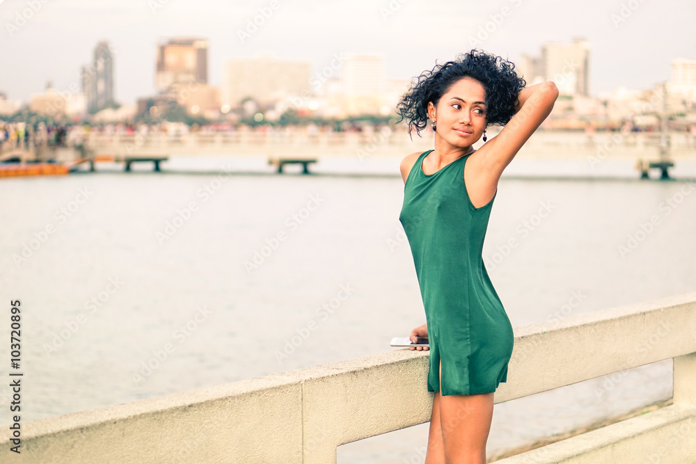 Beautiful young woman at pier standing in sensual posing - Slim body latina girl holding  mobile relaxing at city sea view - Asian fashion model wearing green short dress by the river - Beauty concept