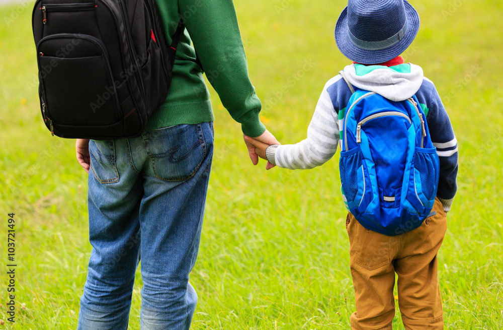 father holding hand of little son with backpack outdoors father holding hand of little son with backpack outdoors