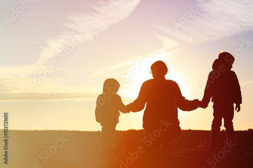 father and two kids travel at sunset