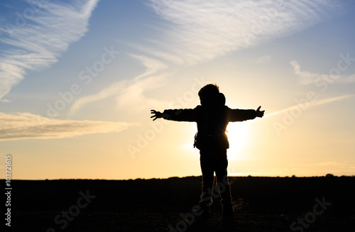 Silhouette of happy little boy travel at sunset