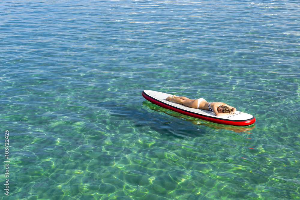 Woman relaxing over a paddle surfboard Woman relaxing over a paddle surfboard