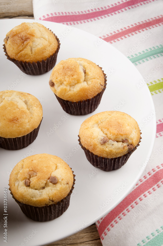 chocolate chips muffins on a white cake stand
