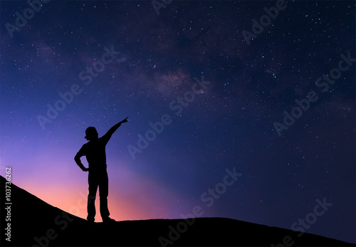 Sillhouette of woman standing next to the milky way and pointing