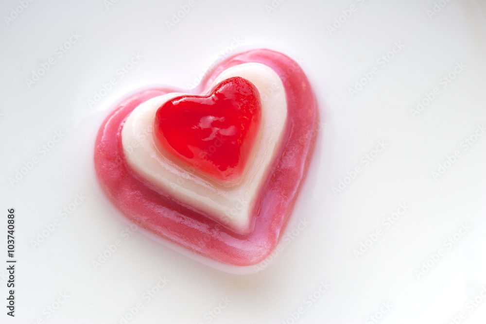 Red candy heart on a milk background.