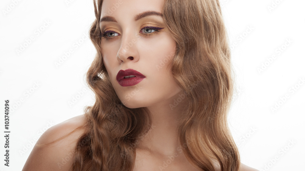 Young fashionable blonde model with wavy hairstyle and gorgeous vintage makeup posing against white studio background Young fashionable blonde model with wavy hairstyle and gorgeous vintage makeup posing against white studio background