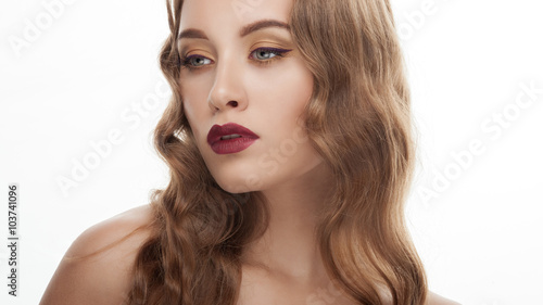 Young fashionable blonde model with wavy hairstyle and gorgeous vintage makeup posing against white studio background